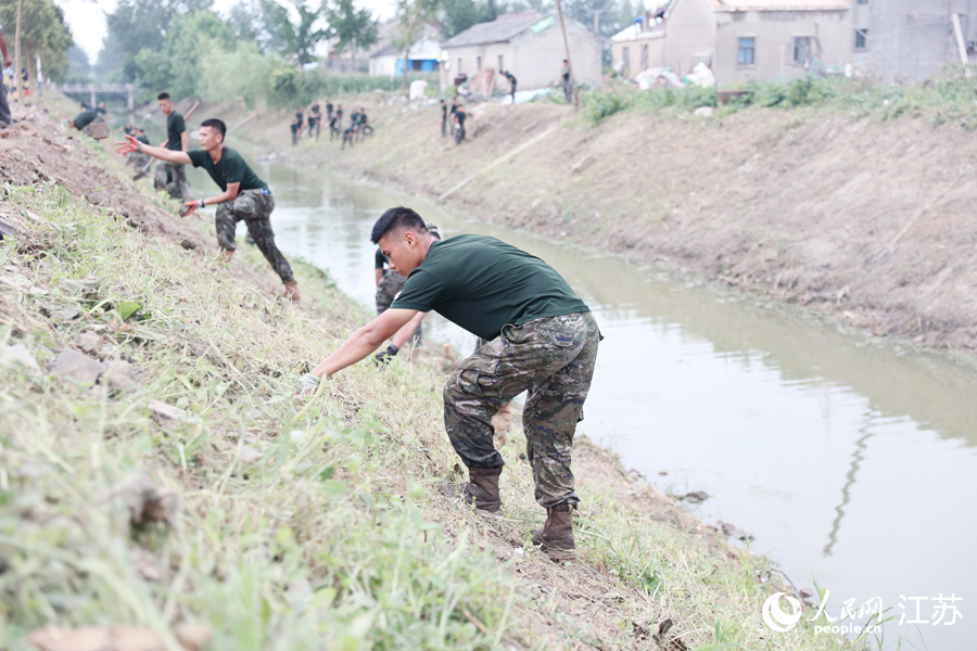 武警官兵幫助百姓清理河堤。人民網(wǎng) 余樂(lè)攝